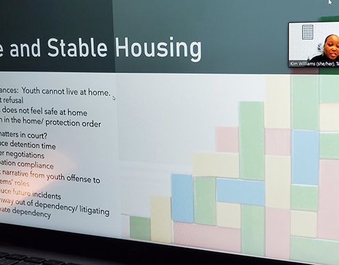 A small photo of Kim appears in the upper right corner of a presentation slide that reads: Safe and Stable Housing.