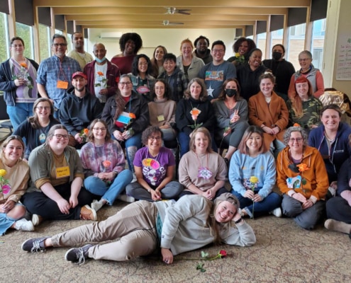 TeamChild staff and several board members are gatheres for a group portrait. Several people hold roses and everyone is wearing a creative neametag they made at the retreat.